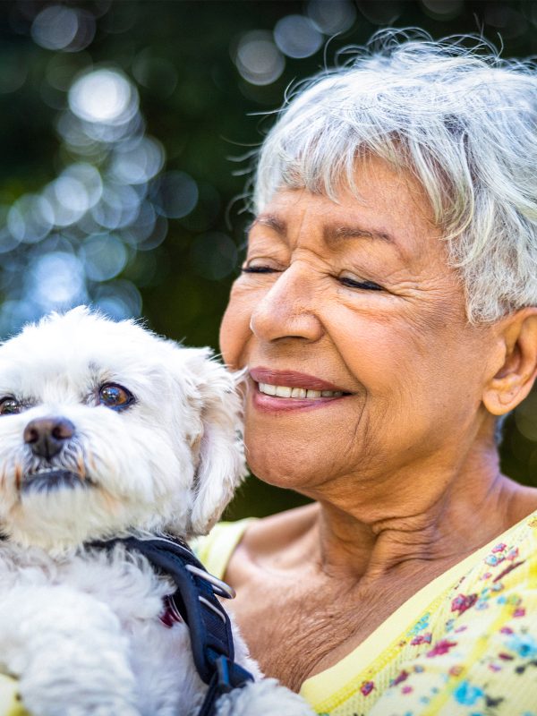 Happy senior woman with her dog, hugging thinking about leaving a gift in a will as a bequest