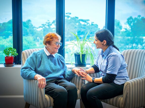 BAPTCARE Wyndham Lodge resident and staff member chatting with a view to the trees outside