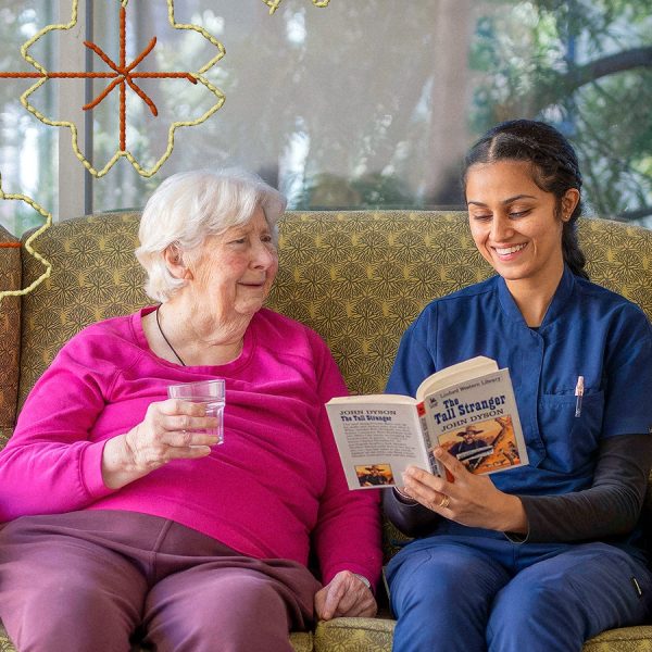 A residential aged care client sitting on a couch with a BaptistCare staff member