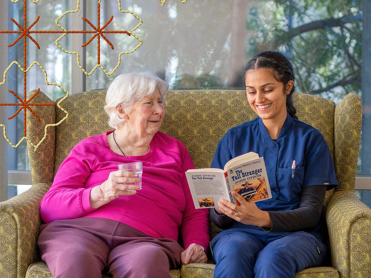 Older client sitting on a lounge beside a staff member